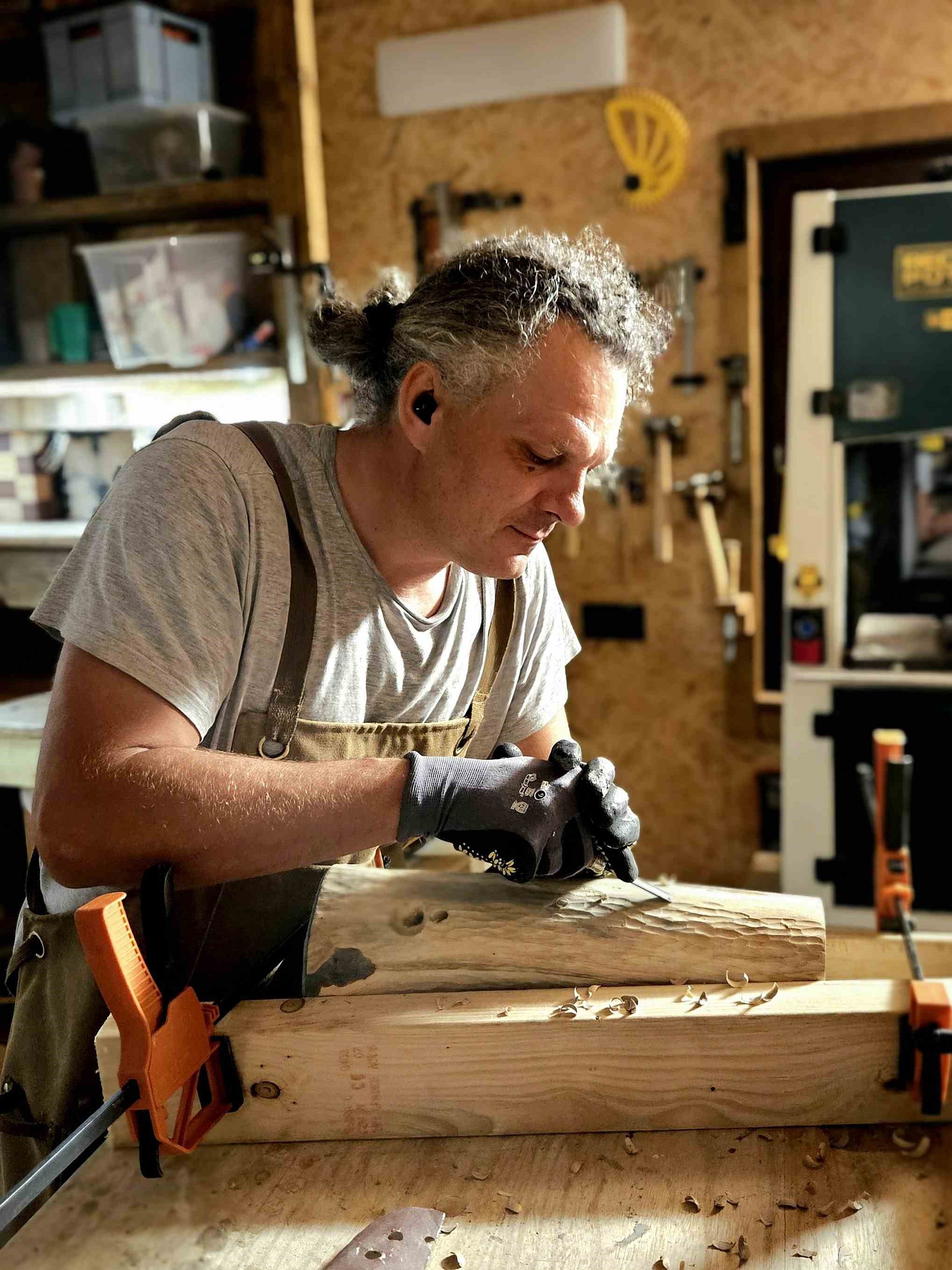 Jakub Chmiel przy pracy nad drewnianą lampą